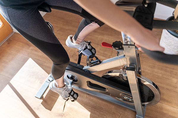 Low section view of a young woman in sportswear exercising on exercise bike at home